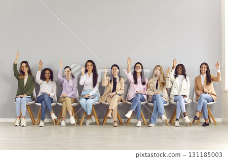 Group of happy women raising their hands to ask questions at business conference 131185003