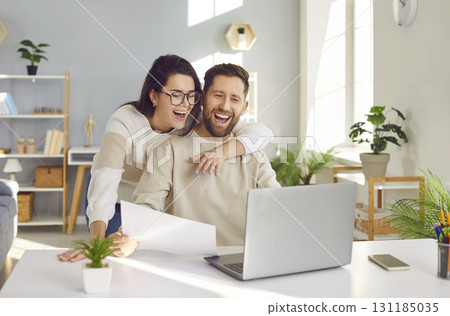 Happy young family couple using their laptop computer and paying their bills online 131185035