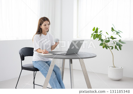 A woman enjoying coffee while using a computer 131185348