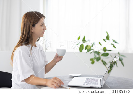 A woman enjoying coffee while using a computer A woman enjoying coffee while using a computer 131185350