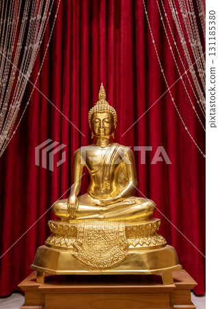 A golden Buddha image in the meditation posture, subduing Mara, against a red curtain at Wat Tha Sung. 131185380