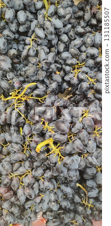 Dark reddish-blue grapes with translucent, tender, and juicy flesh. A container filled with grapes. 131185507