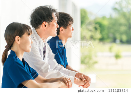 Male and female doctors, physicians, nurses, medical staff and technicians taking a break outdoors at the hospital 131185814