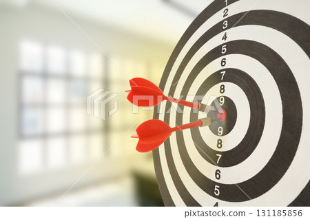 Red darts are striking the bullseye of a dartboard indoors 131185856