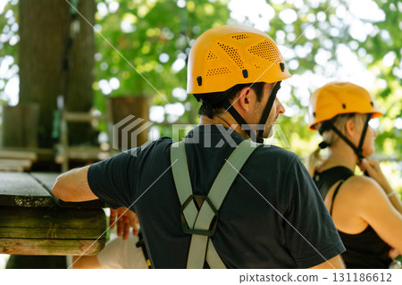Back view of man in climbing harness listening to instructor outdoors 131186612