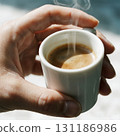 Hand Holding a Steaming Cup of Espresso 131186986