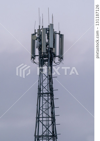 Metal tower with multiple cellular repeaters against cloudy sky. 131187126