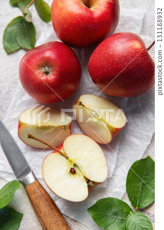 Freshly cut red apples on baking paper with knife and leaves Freshly cut red apples on baking paper with knife and leaves 131188932