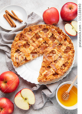 Apple pie with slice removed surrounded by fresh apples 131188940