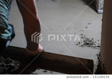 Builder worker master making cement floor screed in rough finishing apartment. 131189134