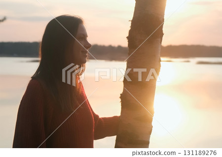 Thoughtful smiling woman admiring nature, lake in dark at sunset in summer. Thoughtful smiling woman admiring nature, lake in dark at sunset in summer. 131189276