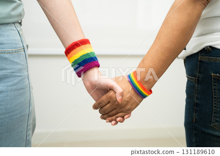 Asian LGBT couple woman holding hand wearing rainbow wristband. Asian LGBT couple woman holding hand wearing rainbow wristband. 131189610