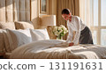 Professional hotel housekeeper in white uniform making luxury bed with crisp linens in elegant sunlit room with flowers and neutral decor 131191631