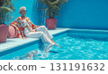 Stylish woman in colorful kimono relaxing poolside with feet in crystal blue water at luxury resort spa vacation destination 131191632