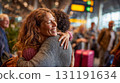 Joyful reunion embrace between two women at busy airport terminal with luggage showing emotional homecoming and travel connection moment 131191634