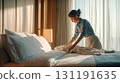 Professional hotel housekeeping staff carefully arranging fresh white towels on luxury hotel bed in elegant room with natural window lighting and modern decor 131191635