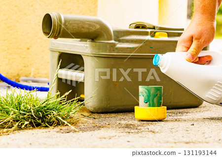 Man serving caravan, tank toilet cassette in dump station. 131193144