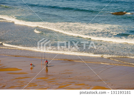 Angler with fishing rod on sea shore 131193181