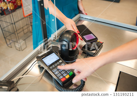 Cashier scanning customer's smartphone for payment at supermarket checkout 131193211