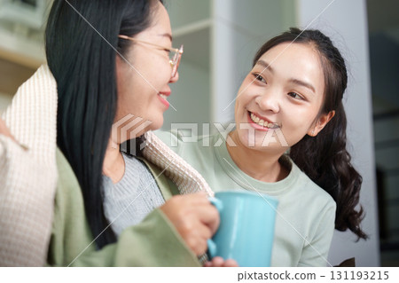 Joyful Connection: Women sharing tea and smiles in a cozy home 131193215