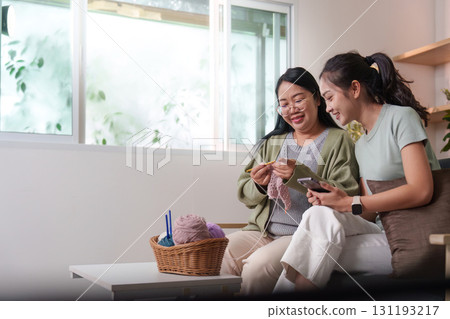 Creative Bonding: Two women knitting together while enjoying technology 131193217