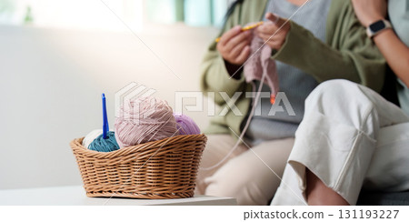 Knitting Essentials: Colorful yarn basket and hands at work in a cozy space Knitting Essentials: Colorful yarn basket and hands at work in a cozy space 131193227