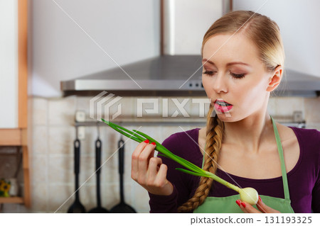 Woman in kitchen holds green fresh chive 131193325