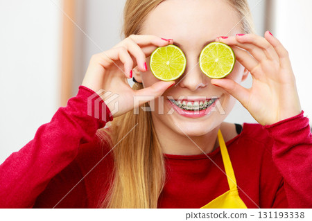 Woman holding fruit lemon half on eyes Woman holding fruit lemon half on eyes 131193338