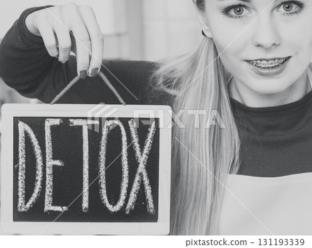 Happy woman holding board with detox sign Happy woman holding board with detox sign 131193339
