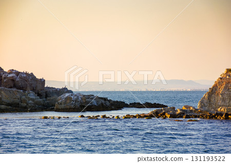 rock island view on black sea in evening light. rough landscape with calm waves for summer adventures background at the sea under blue sky with clouds 131193522