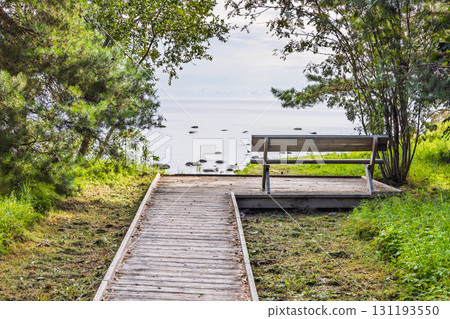 Tranquil Baltic coast with wooden path and bench overlooking serene blue seascape 131193550