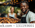 Man is smiling and holding a fork and knife, while a woman stands behind him 131193601
