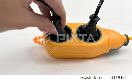Hand plugging power cable into outdoor waterproof orange extension socket, connecting electricity supply, heavy duty electric splitter for garden, construction, camping, isolated on white background Hand plugging power cable into outdoor waterproof orange extension socket, connecting electricity supply, heavy duty electric splitter for garden, construction, camping, isolated on white background 131193663