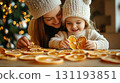 Smiling mother and daughter in cozy sweaters and hats crafting dried oranges at home with festive lights, Concept of sustainable holiday decor and craftwork, eco friendly, sustainable, zero waste 131193851
