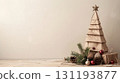 Handmade paper Christmas tree with pine branches, cones, and ornaments on wooden surface and beige background, concept of eco-friendly decor 131193877
