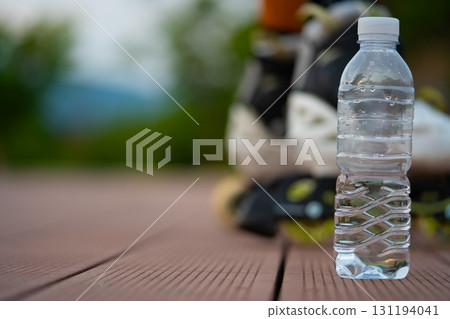 A bottle of clean water and a roller skates. After exercise on a summer evening. 131194041
