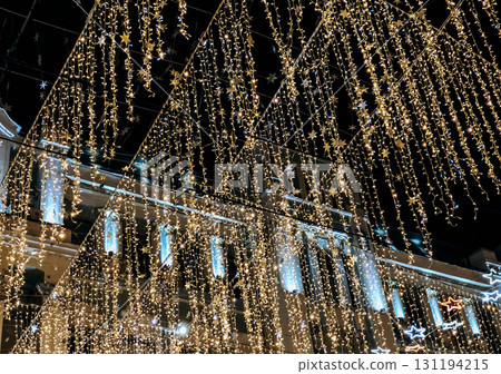 A mesmerizing night shot of a street or public square ceiling, covered by thousands of shimmering golden and blue fairy lights 131194215