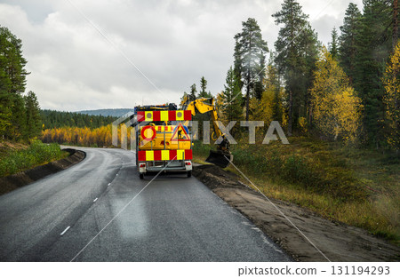 Road maintenance vehicle with excavator working on roadside in autumn forest Road maintenance vehicle with excavator working on roadside in autumn forest 131194293