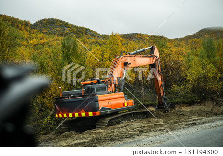 Excavator working on road construction in autumn forest landscape 131194300