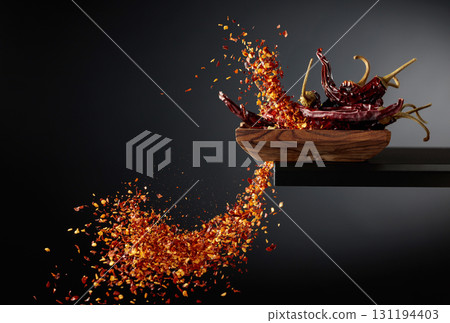 Dry red chili peppers and crushed chili flakes in motion. 131194403