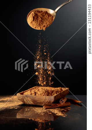 Cinnamon powder is poured into a wooden dish. 131194433