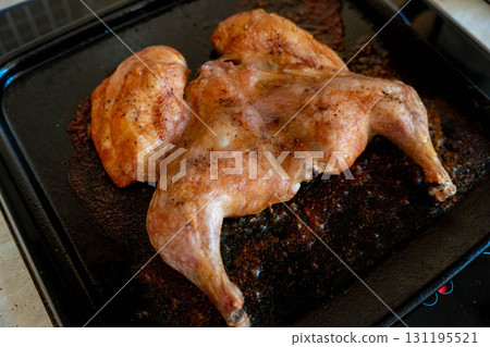 Spatchcocked roasted chicken cooking on baking sheet 131195521