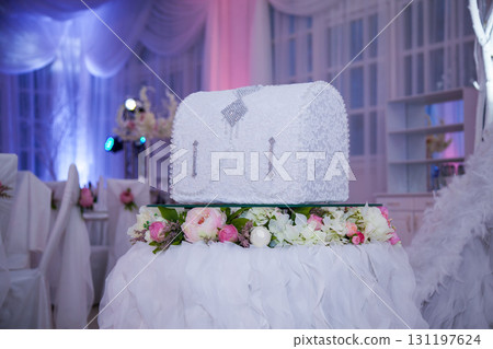 Wedding money box on a flower pedestal surrounded by elegant reception decor 131197624