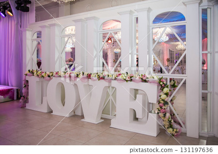Large decorative love sign at a wedding venue decorated with flowers and soft lights in the evening Large decorative love sign at a wedding venue decorated with flowers and soft lights in the evening 131197636