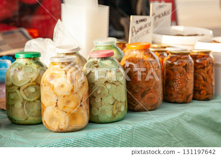 Pickled Different mushrooms in large glass jars at the russian rural fair. Ginger 131197642
