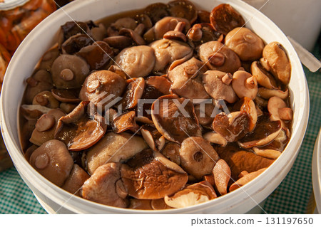 Pickled boletus mushrooms in a plastic bucket at the russian fair. Altai salted mushrooms - maslyata 131197650