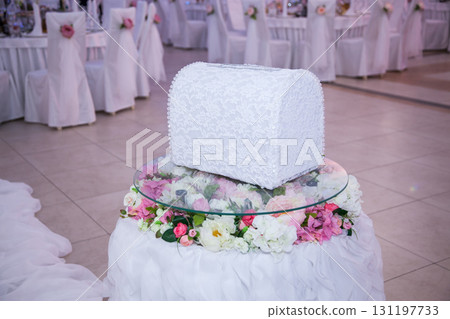 Elegant wedding money box on floral pedestal amidst reception decor Elegant wedding money box on floral pedestal amidst reception decor 131197733