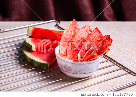 Winter supplies: slices of dried watermelon with fresh pieces on light background with grid Winter supplies: slices of dried watermelon with fresh pieces on light background with grid 131197750