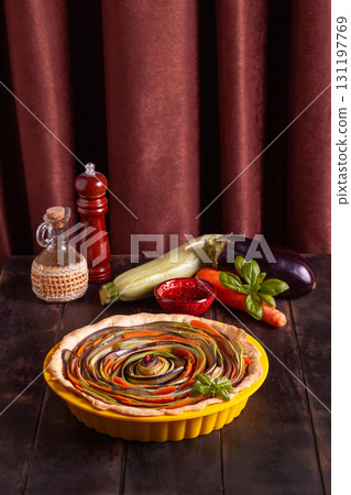 Process of cooking vegetable spiral tart with zucchini, eggplant, carrots, bell pepper, basil in silicone baking dish 131197769