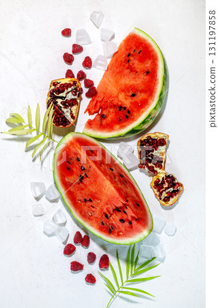 Summer background: slices of fresh watermelon with pomegranate fruit, raspberry, ice, palm leaf on white background Summer background: slices of fresh watermelon with pomegranate fruit, raspberry, ice, palm leaf on white background 131197858